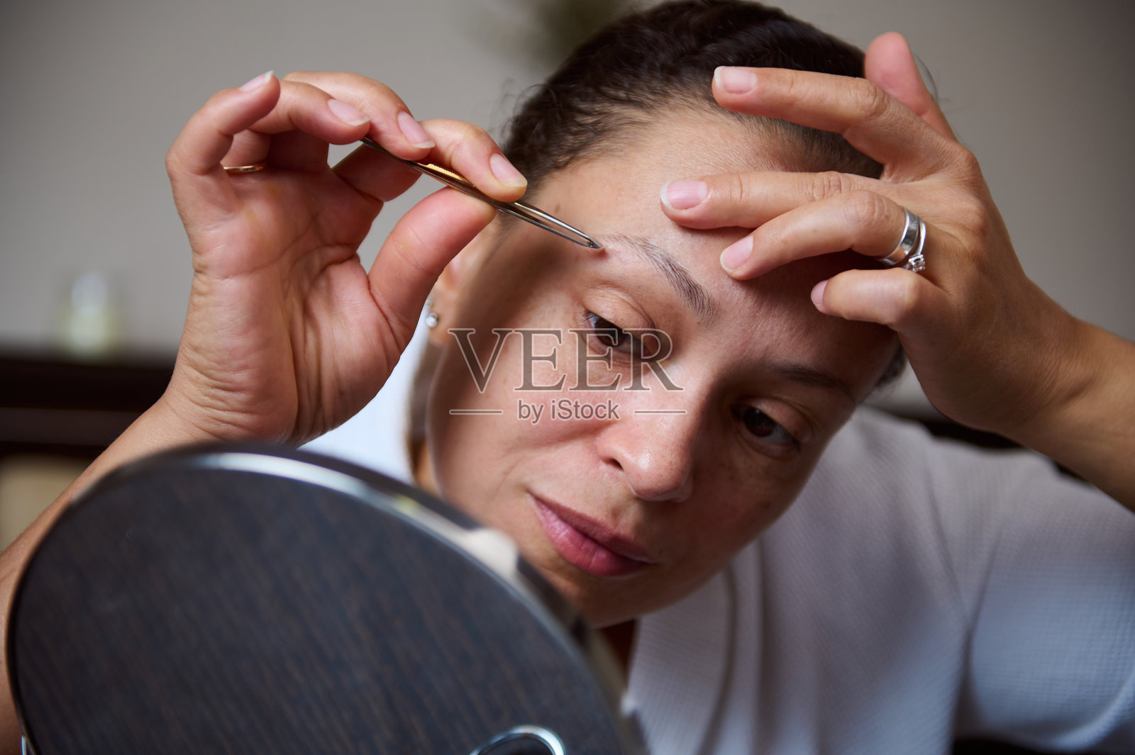 女人在家镜子前修眉毛照片摄影图片