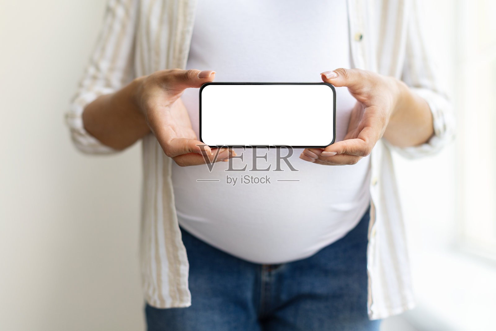 非裔美国孕妇在家中展示一部空白屏幕的智能手机照片摄影图片