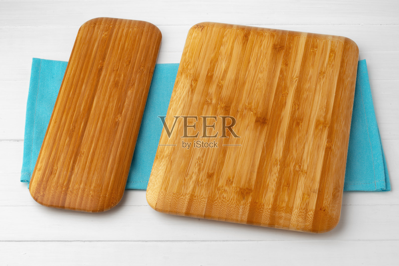 白色木桌上的棉布餐巾上的木质切菜板照片摄影图片