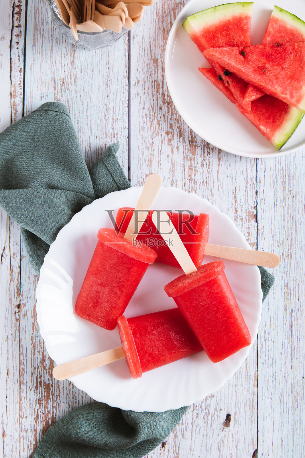 红色西瓜冰棒冰淇淋放在桌子上的盘子里，垂直视角。照片摄影图片