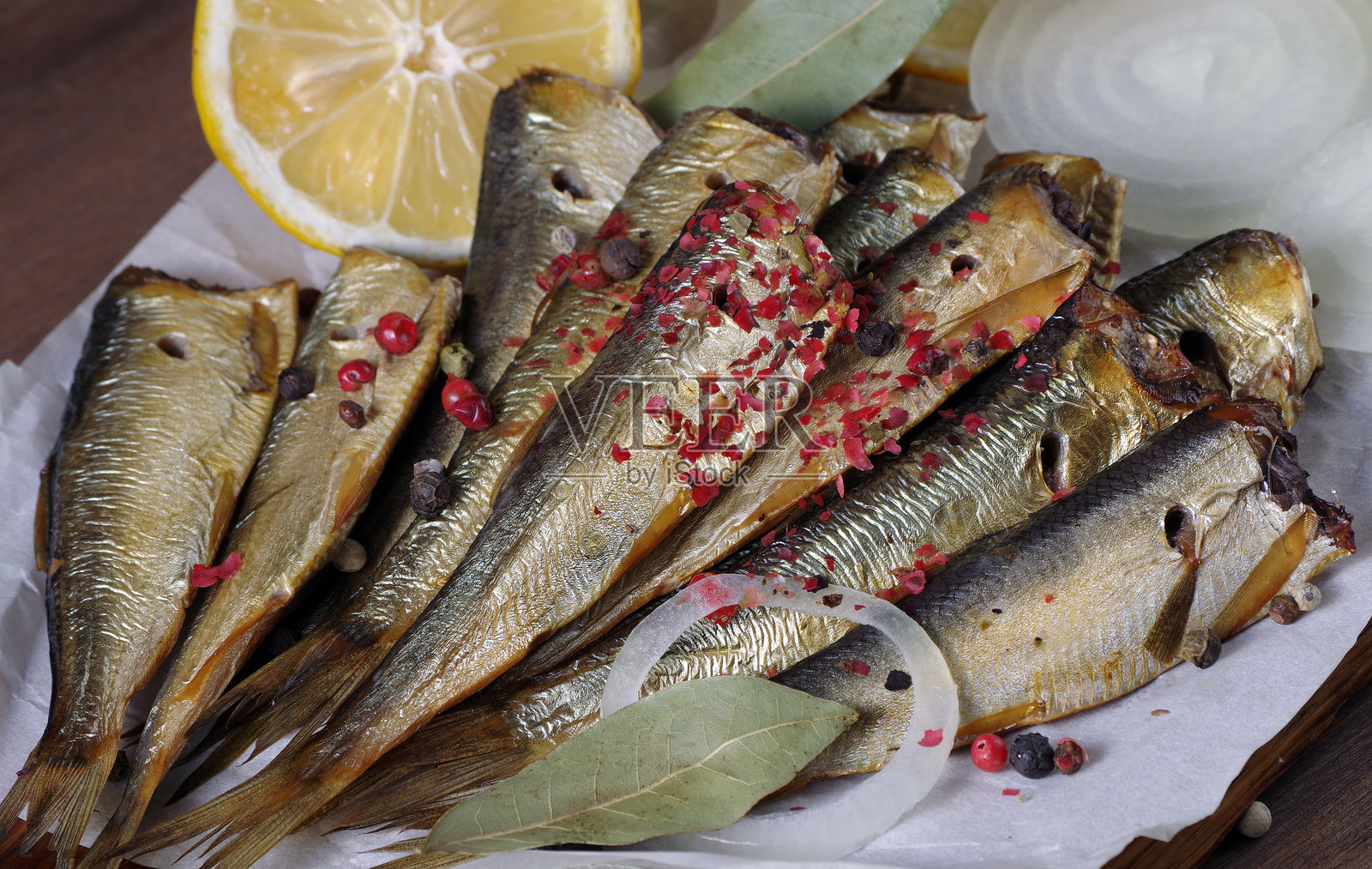 烟熏鱼和香料特写。烟熏小鱼配粉红和黑胡椒照片摄影图片