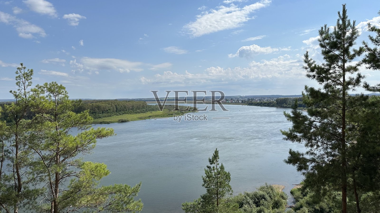 蓝天上漂浮着白色蓬松的积云和卷云，映衬着一条平滑的大河。美丽的晚夏风景。照片摄影图片