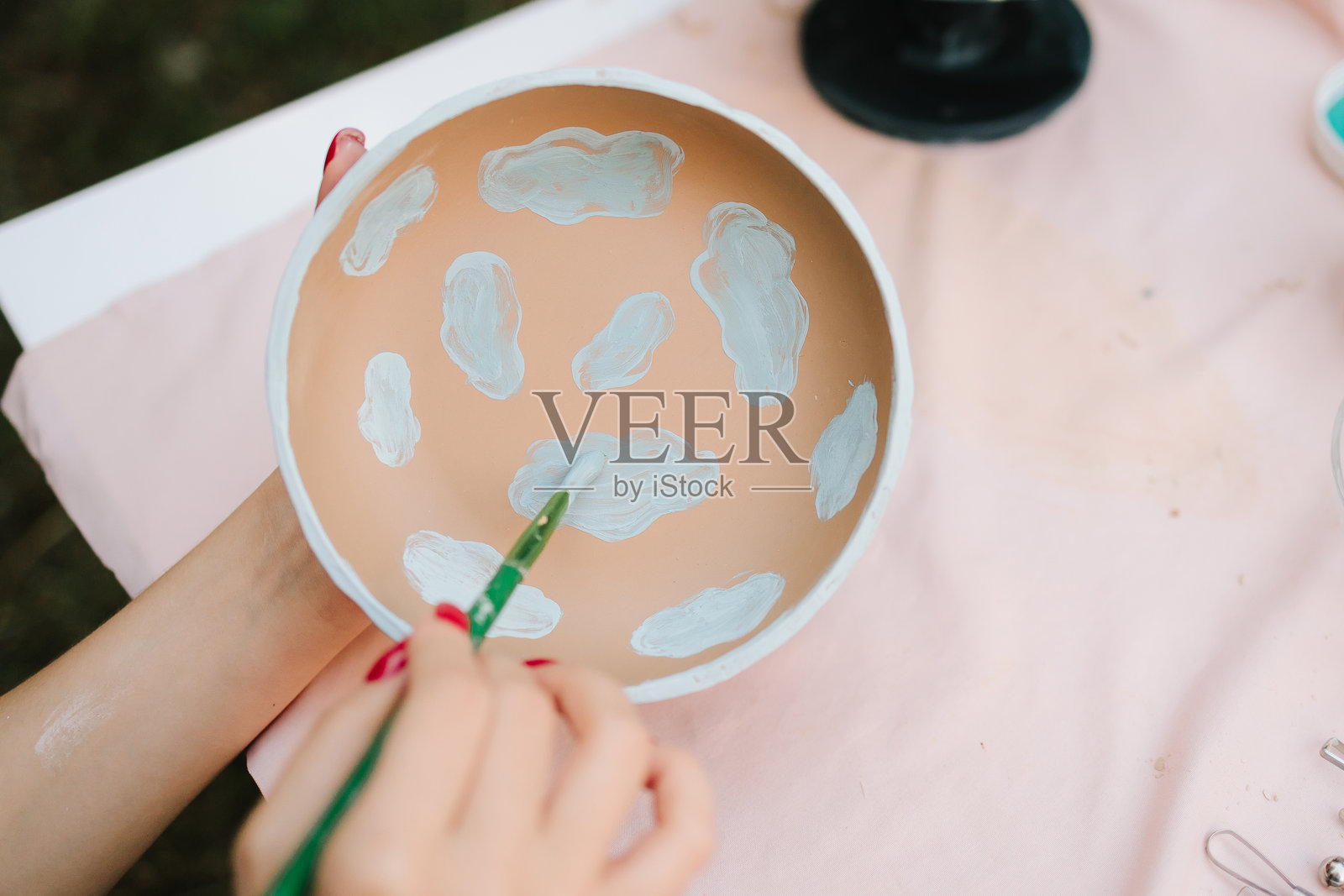 陶艺与陶瓷艺术。陶碗上绘制蓝色云朵。陶碗手工绘制了浅蓝色的云朵，展示了创意的陶艺装饰。照片摄影图片