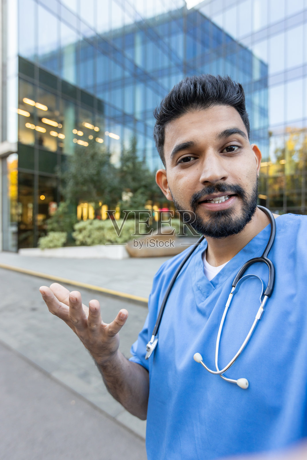 一位微笑的医生站在户外，张开手势，象征着关怀和帮助。照片摄影图片