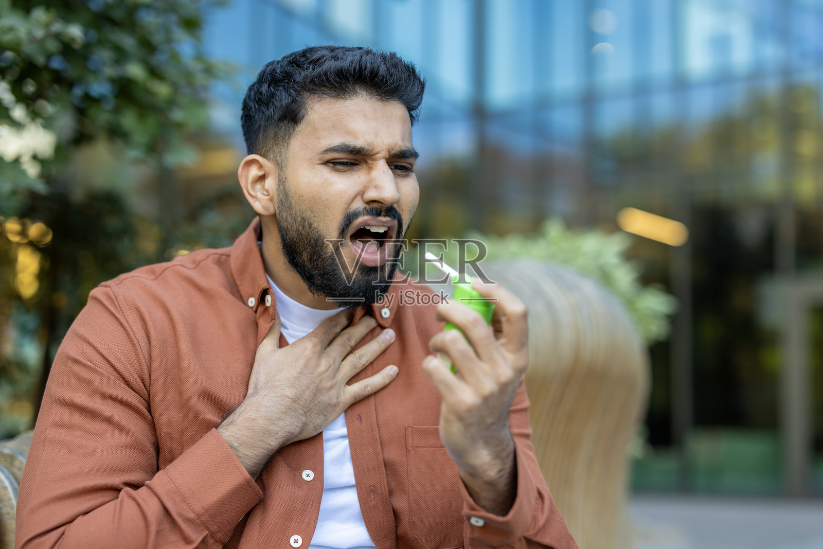 一名男子使用喉咙喷雾来缓解喉咙不适，并可能治疗心绞痛，面露不适之色。照片摄影图片