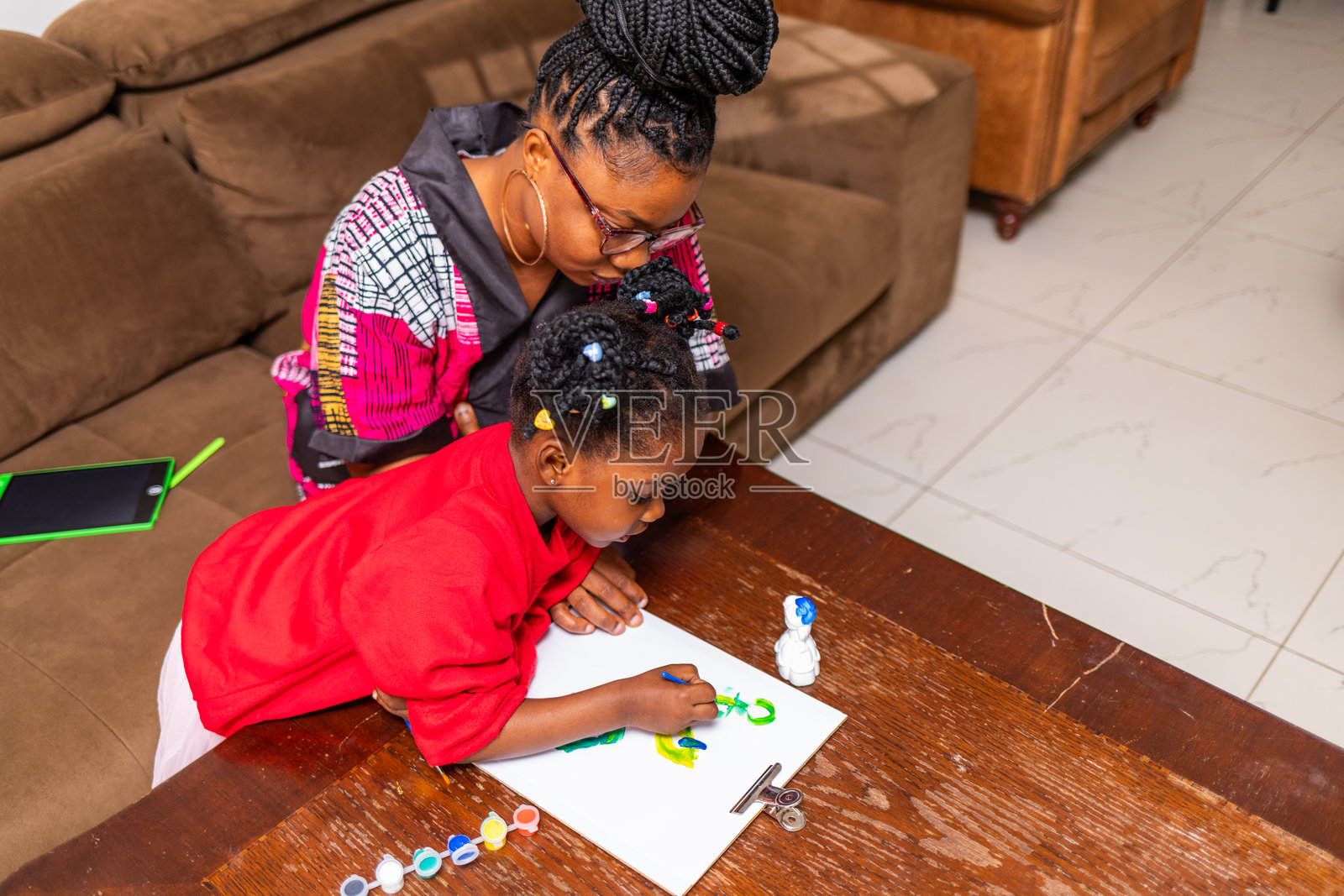 富有创意的艺术。非洲母亲在家中监督她的孩子用画笔和颜料作画。照片摄影图片