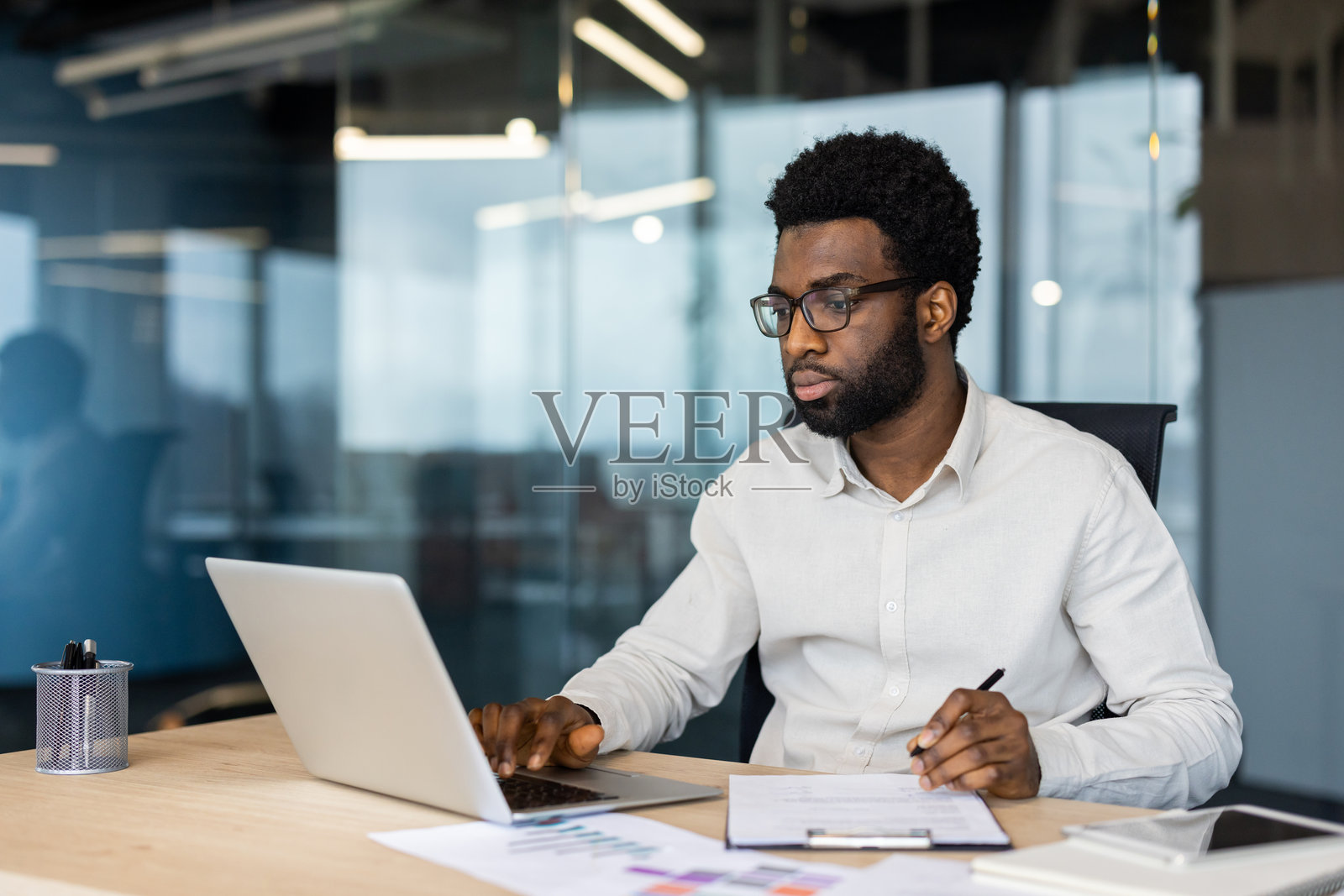 专注的商人在现代办公室里使用笔记本电脑处理文件照片摄影图片