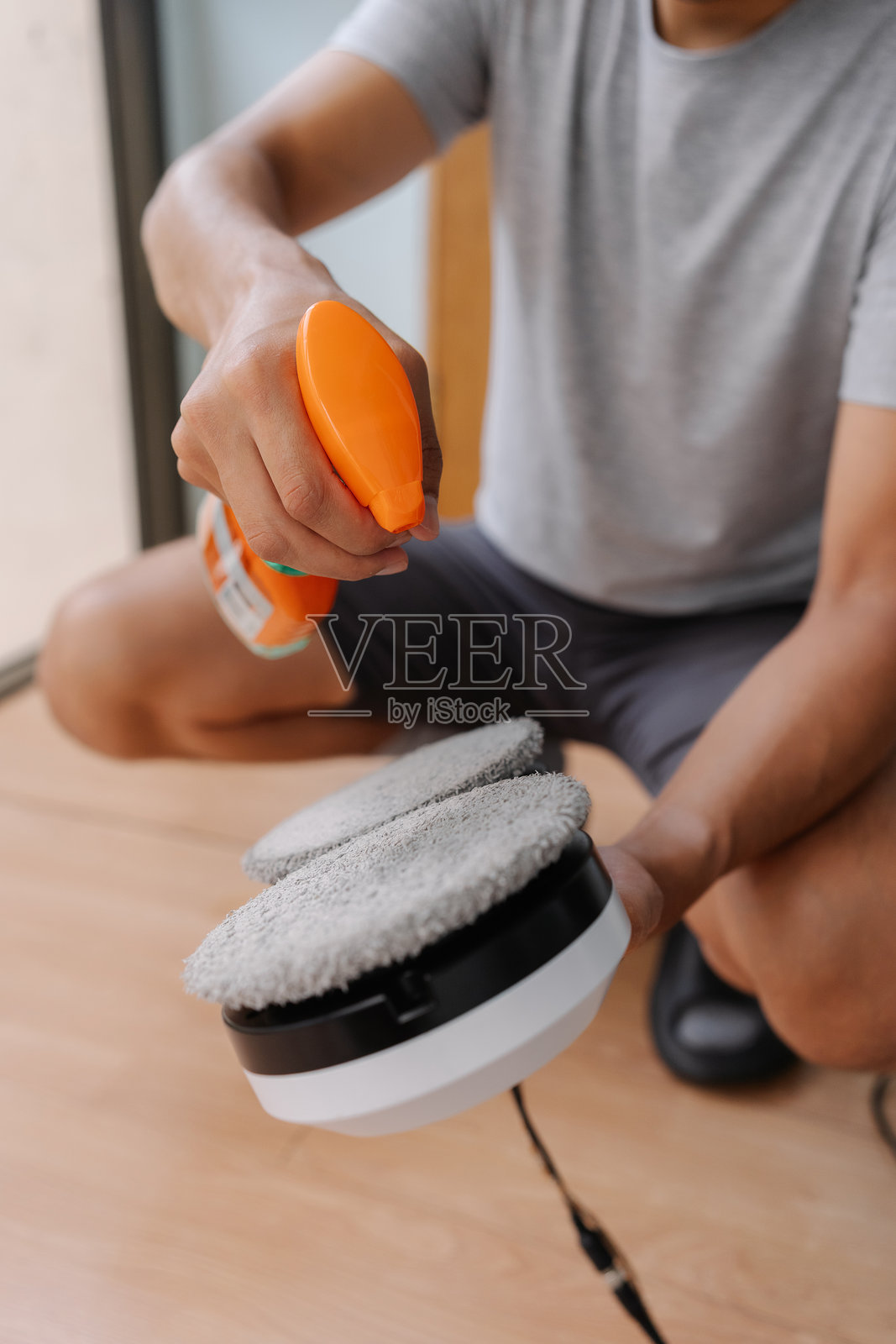 垂直裁剪的镜头，无法识别的窗户清洁工正在准备带有清洁剂喷雾的机器人设备，以优化玻璃表面的维护。照片摄影图片