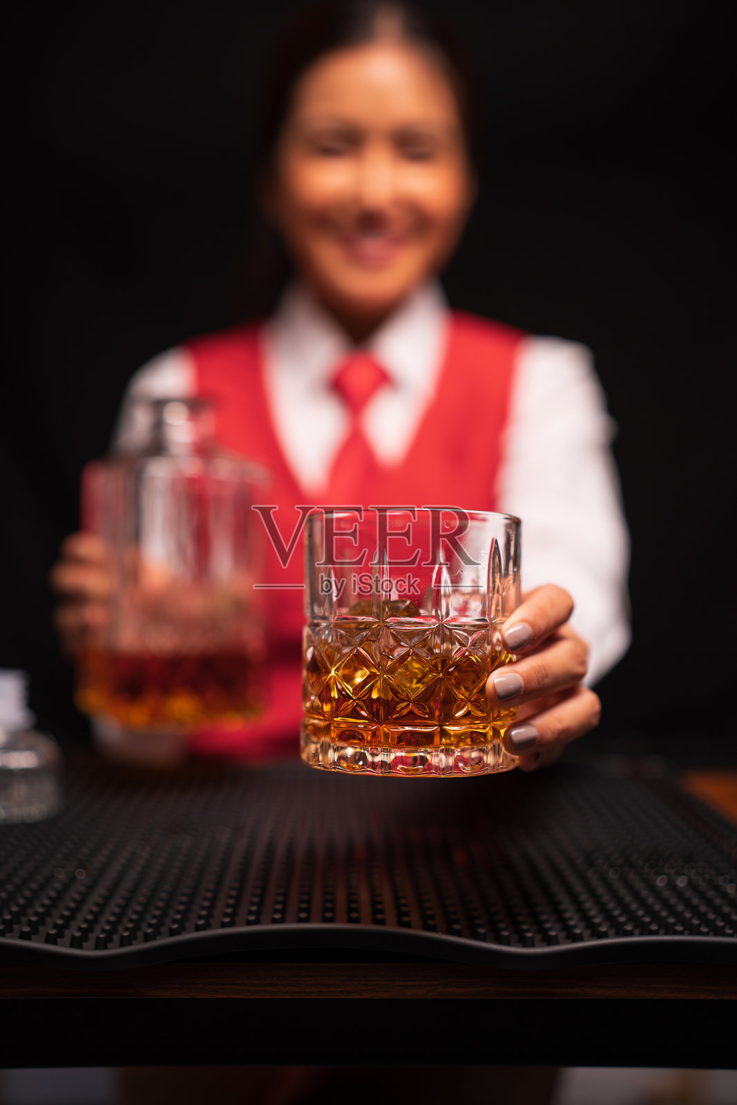 女调酒师在餐厅里将威士忌倒入酒杯。照片摄影图片