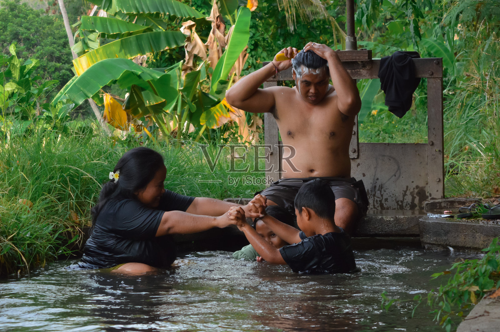父亲在梳理头发，家人们在运河中享受沐浴时光照片摄影图片