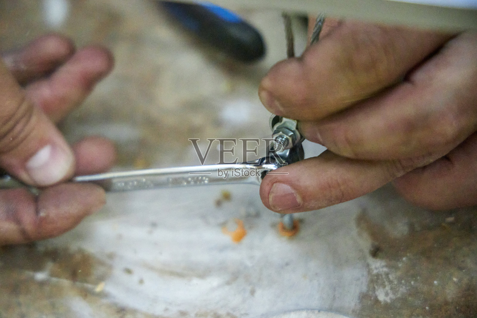 工匠在石面上使用工具，紧固螺栓和修理金属线的特写。手工劳动、建筑、DIY修理和户外技术工作的概念。照片摄影图片
