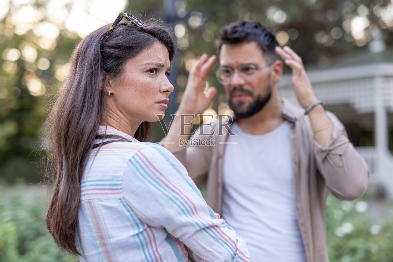 女人坚定地站着，男人在户外环境中做出强调的手势。照片摄影图片
