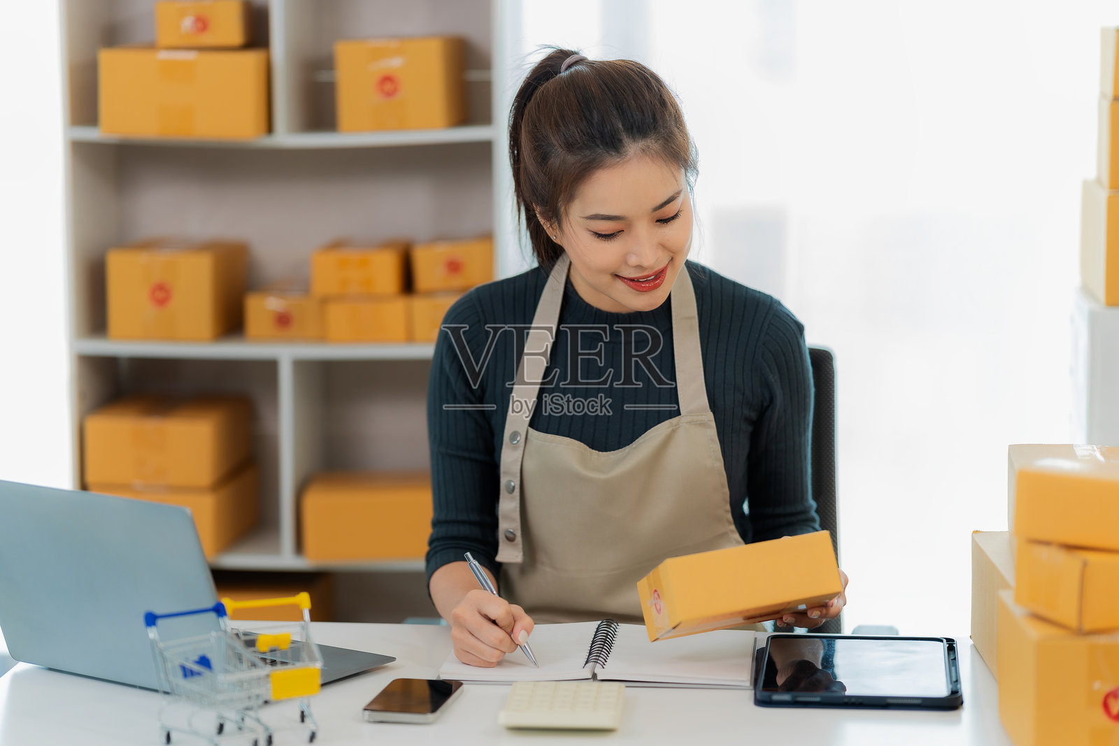 年轻的亚洲女性，中小企业主，在线订单检查员，销售产品，处理箱子，居家和办公室的自由职业工作，在线中小企业。照片摄影图片