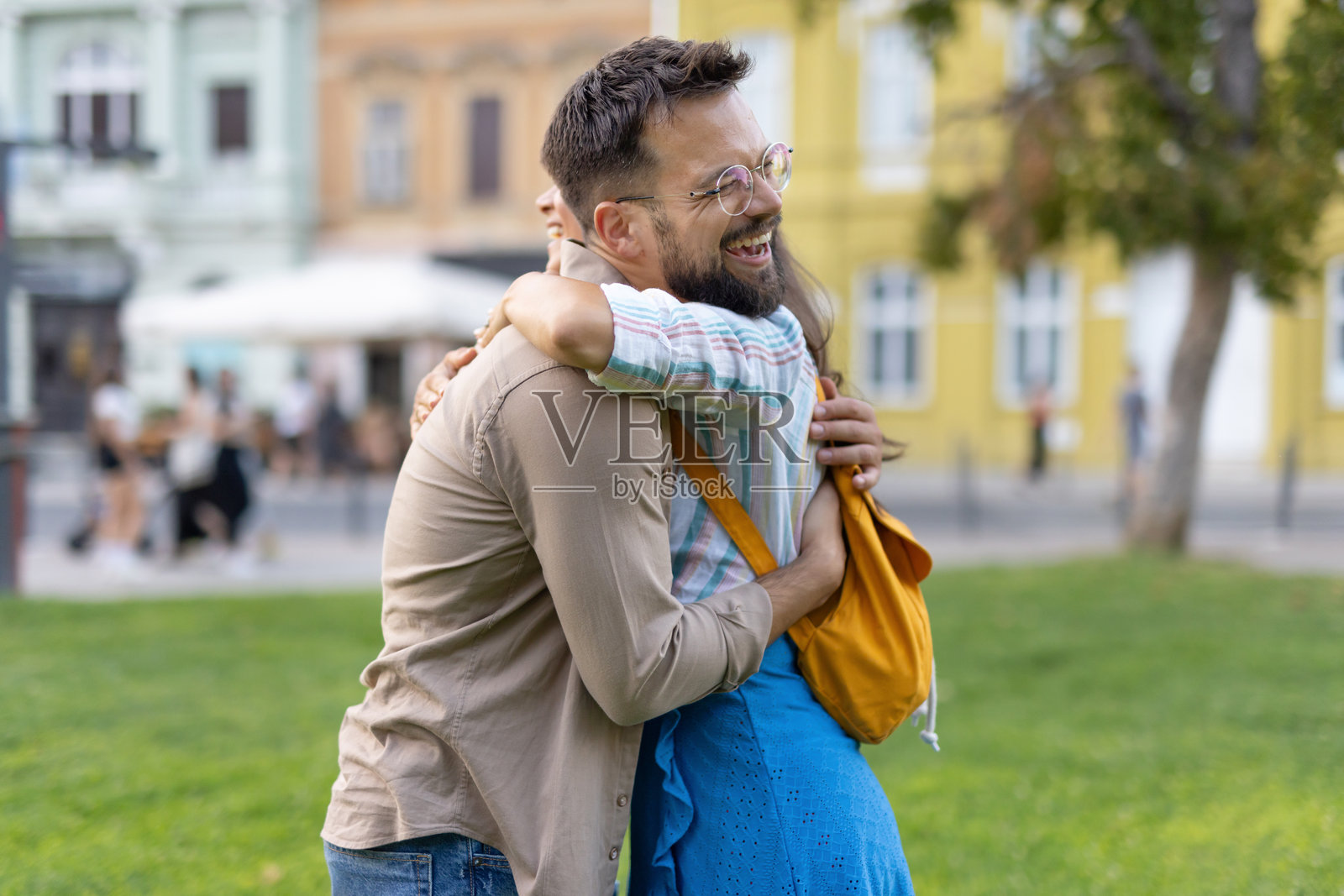 朋友们在公园里欢笑着相拥而抱。照片摄影图片