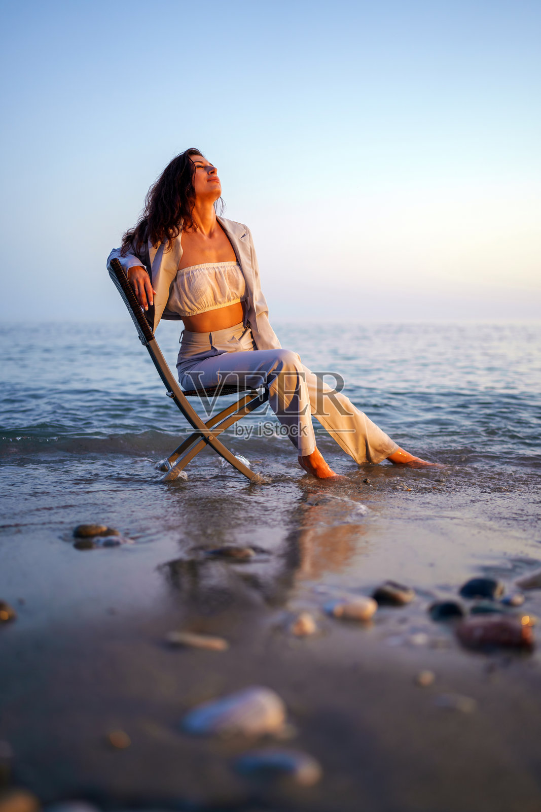 女商人在海滩日落时坐在椅子上放松。照片摄影图片