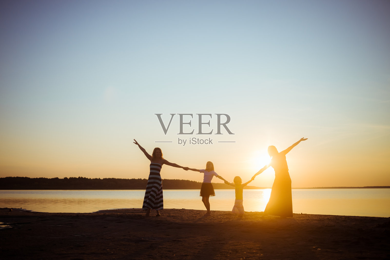 日落光影下人们手牵手的剪影。年轻一代与老一代之间的良好心情和休闲时光。友谊与自由。照片摄影图片