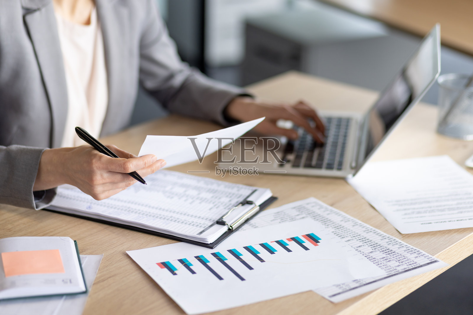 女商人在桌子上用笔记本电脑和文件分析财务数据照片摄影图片