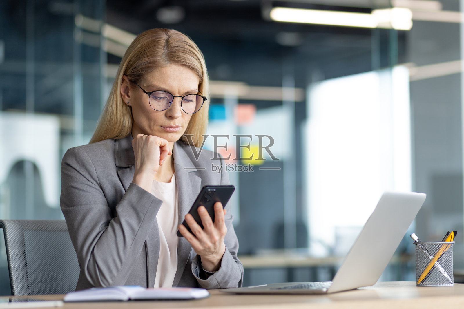 专注于智能手机的女商人在办公室桌子上工作照片摄影图片