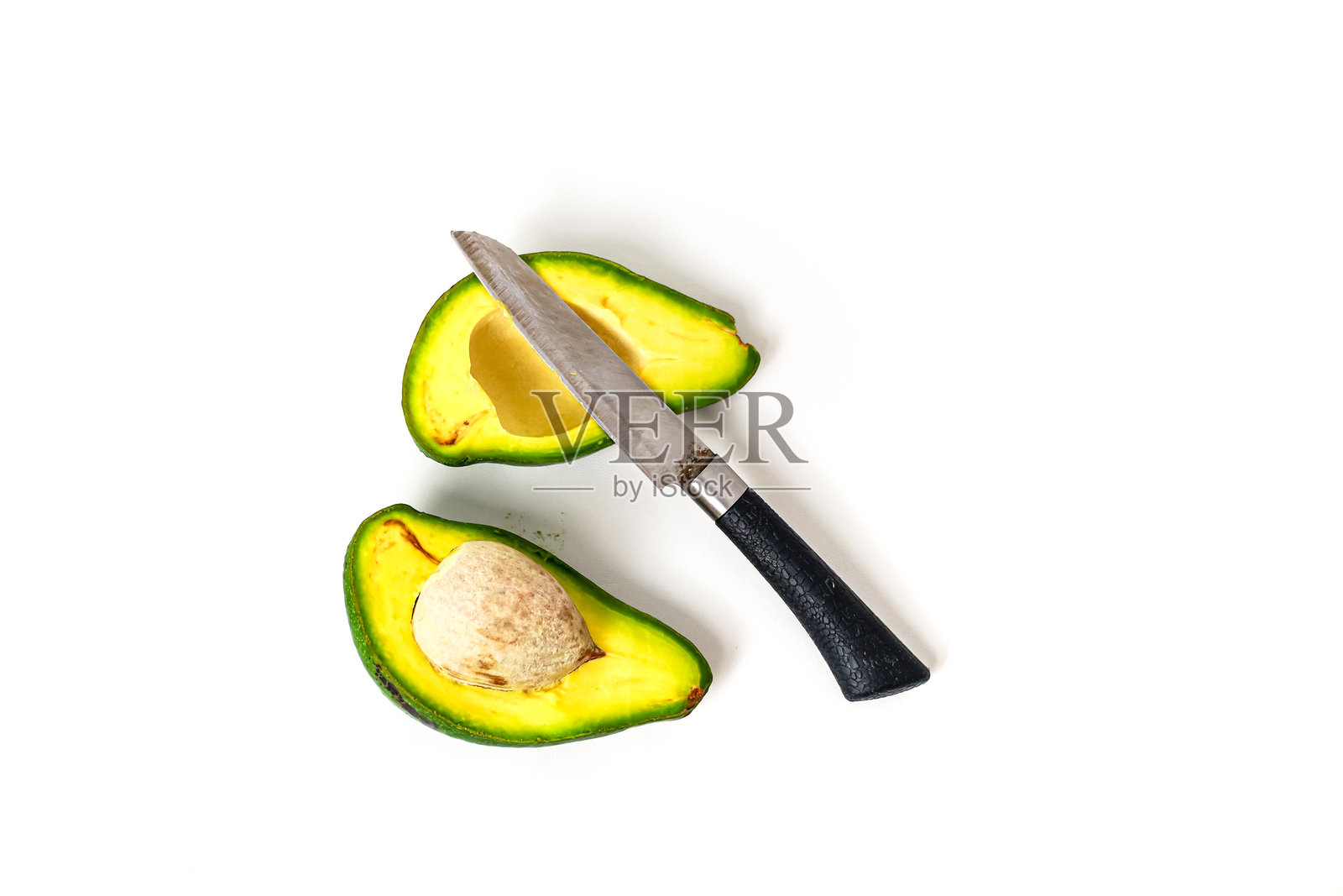 新鲜的鳄梨切成两半，刀子放在白色背景上，展示健康饮食的生活方式照片摄影图片