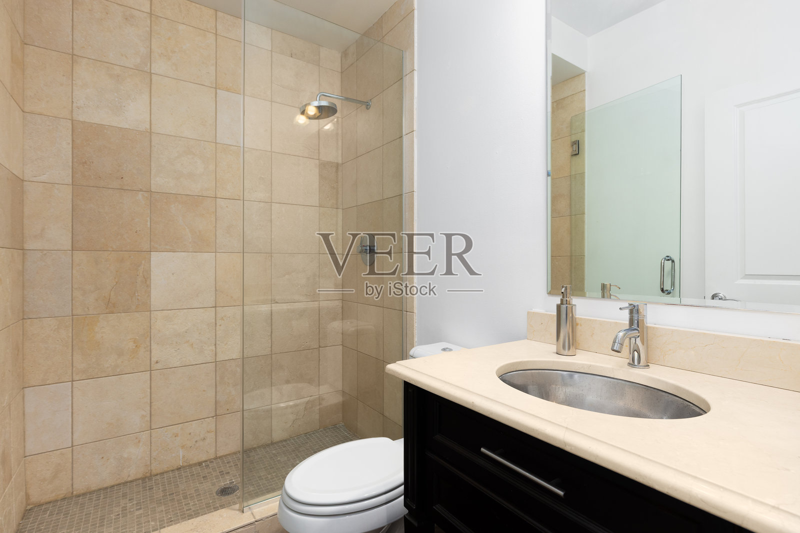 一个带有瓷砖步入式淋浴和深色梳妆台的浴室。照片摄影图片