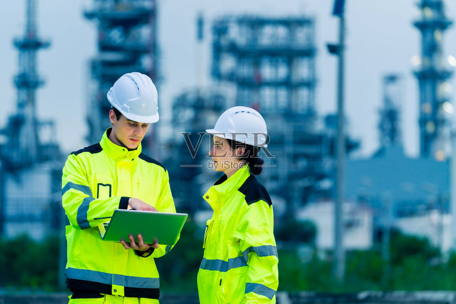 工程师团队在石油炼油厂建设工地上工作。照片摄影图片