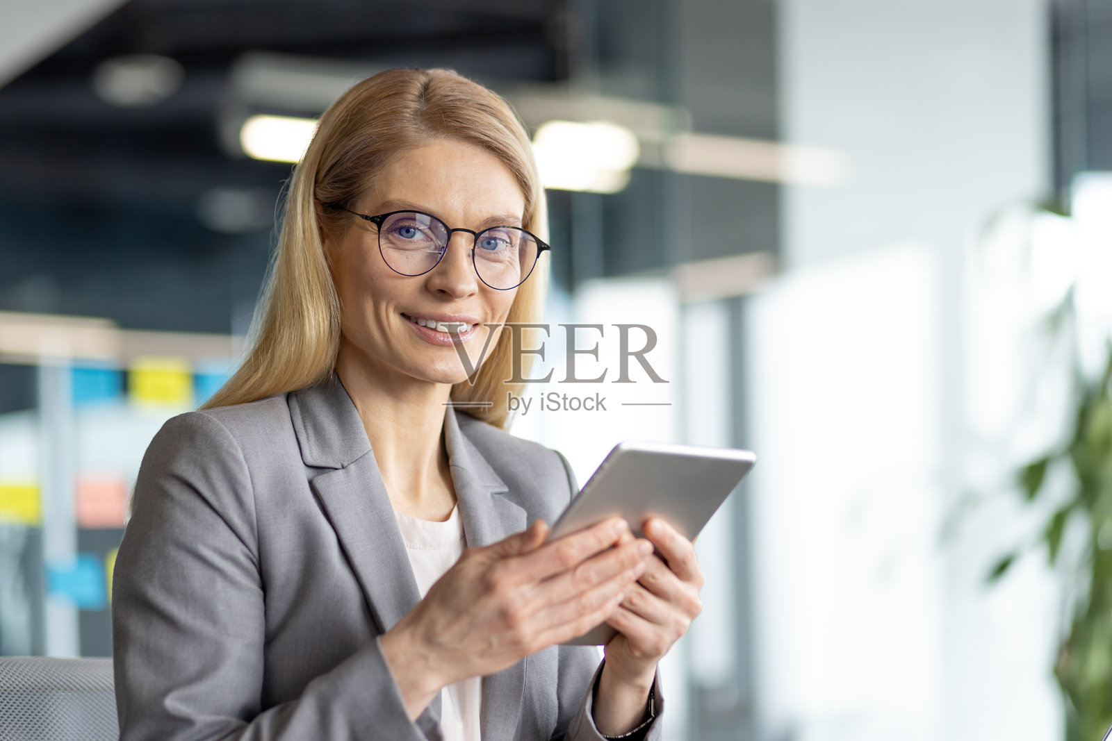 这位女商人专注地在办公室使用平板电脑，脸上带着积极的表情。照片摄影图片