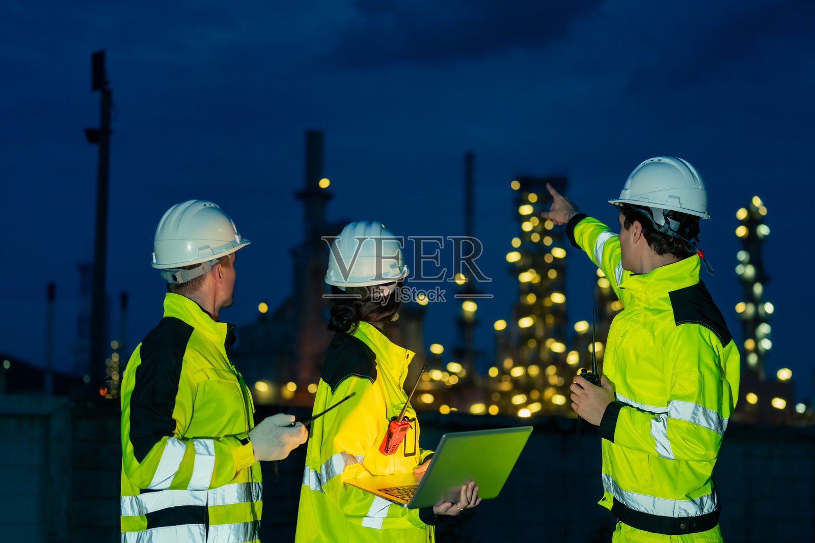 工程师团队在石油炼油厂建设工地上工作。照片摄影图片