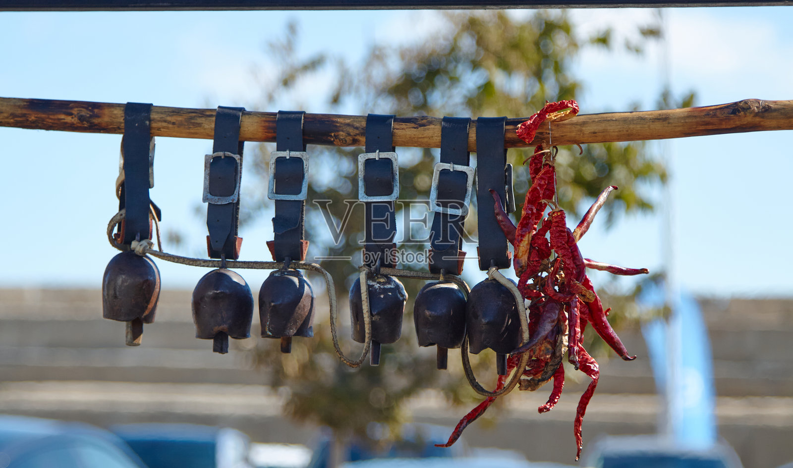 展示装饰配件的陈列，包含悬挂在木梁上的乡村风铃和鲜艳的红辣椒，展现独特的质感和文化魅力，营造迷人的户外环境。照片摄影图片