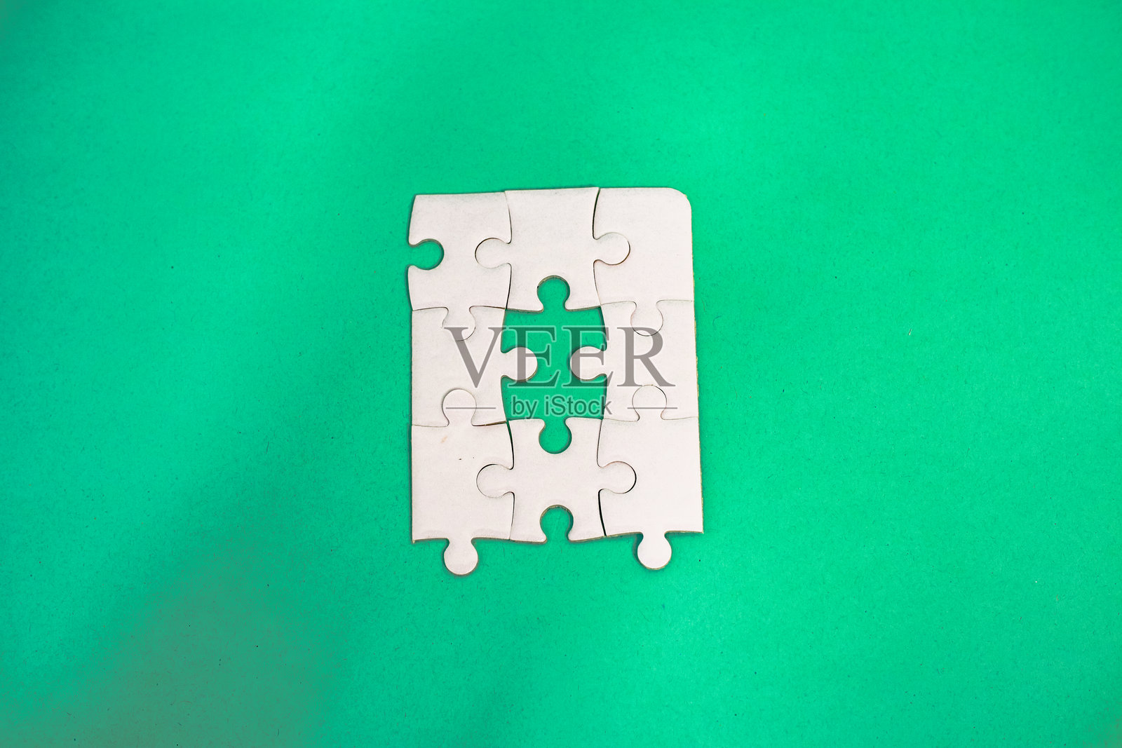 一幅引人注目的俯视角工作室照片，展示了白色拼图与生动的绿色背景。照片摄影图片