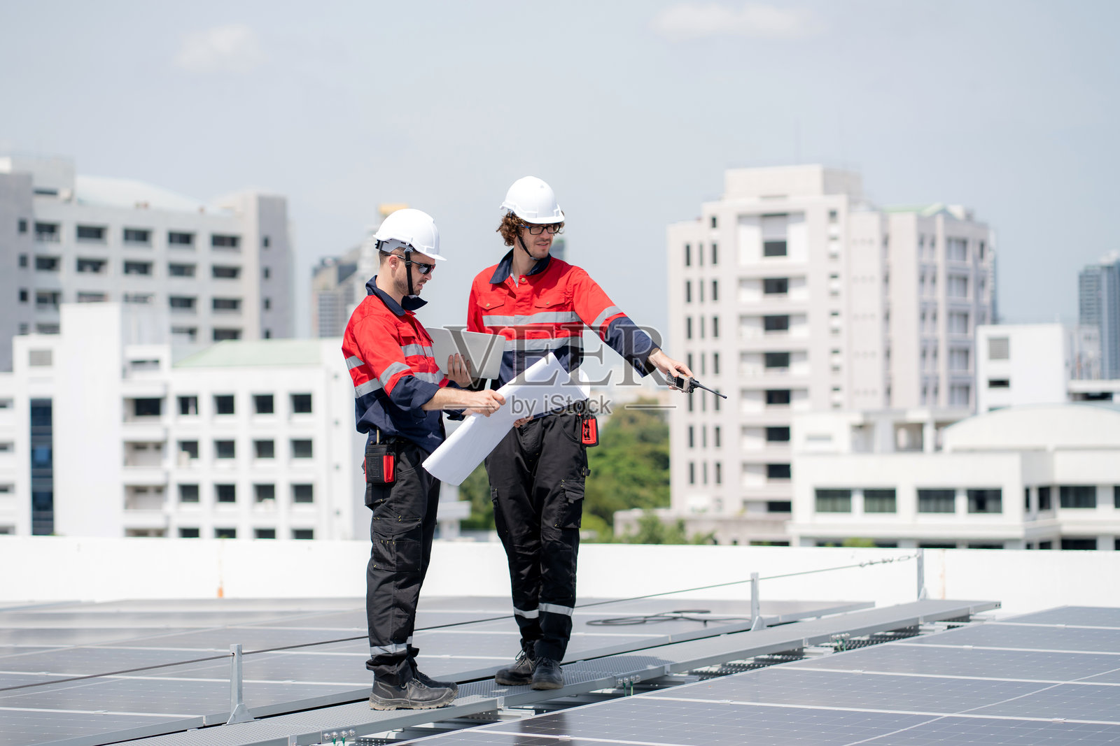 两名工程师一起查看蓝图，检查太阳能系统以规划太阳能电池板的安装，涉及可再生能源和可持续技术，清洁电力、工业和太阳能电池。照片摄影图片