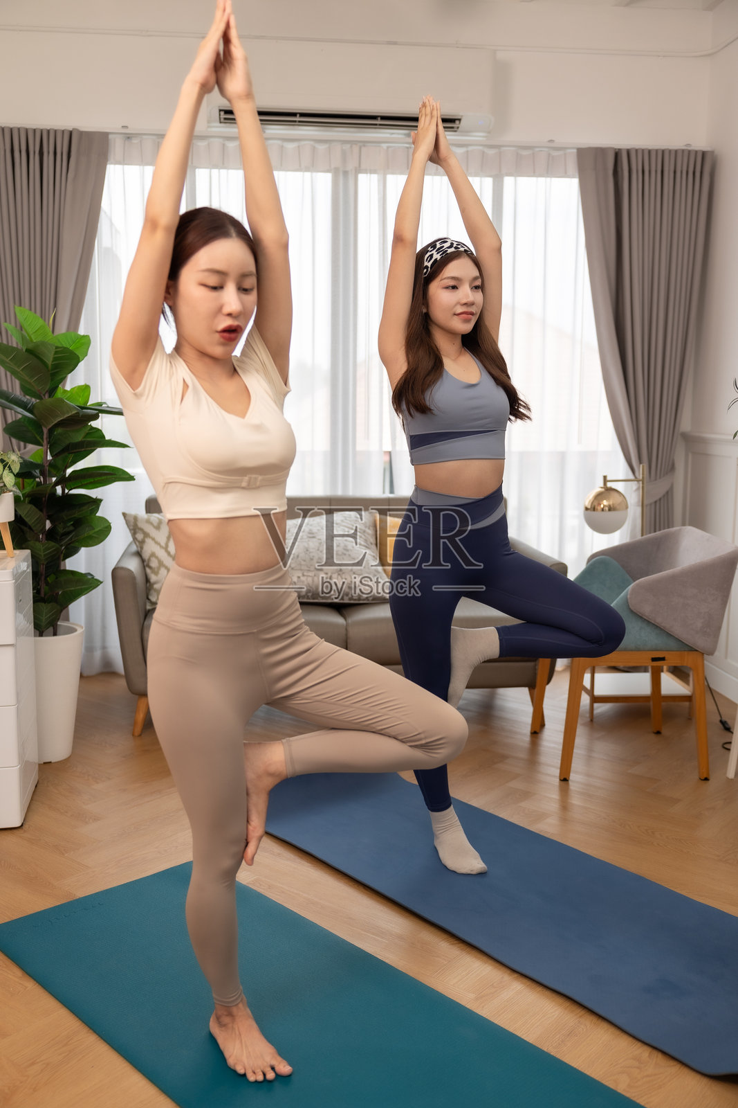 一对情侣，女性在家锻炼。年轻女性在公寓的垫子上观看教程，做瑜伽，使用笔记本电脑。在家训练并观看数字平板上的在线课程。照片摄影图片