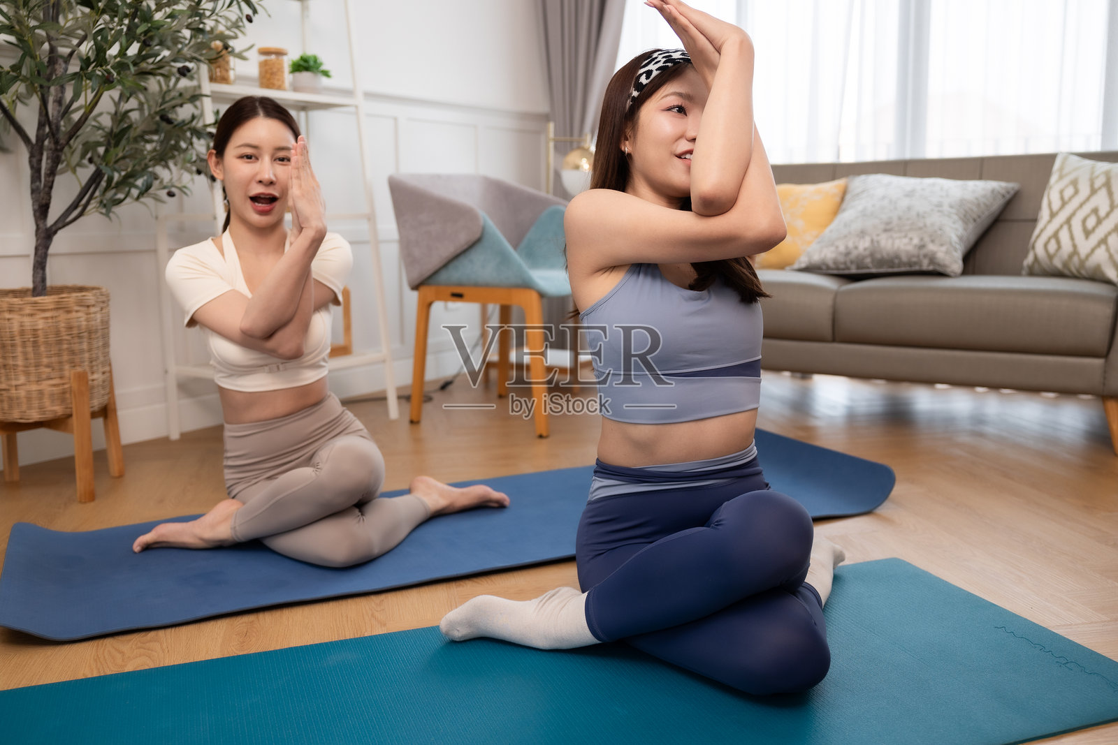 一对情侣，女性在家锻炼。年轻女性在公寓的垫子上做瑜伽，观看教程，使用笔记本电脑。在家训练并观看数字平板上的在线课程。照片摄影图片