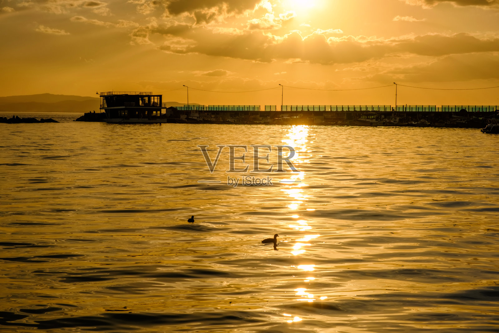 土耳其埃尔德克 - 2024年2月8日：埃尔德克镇港口的日落与船只照片摄影图片