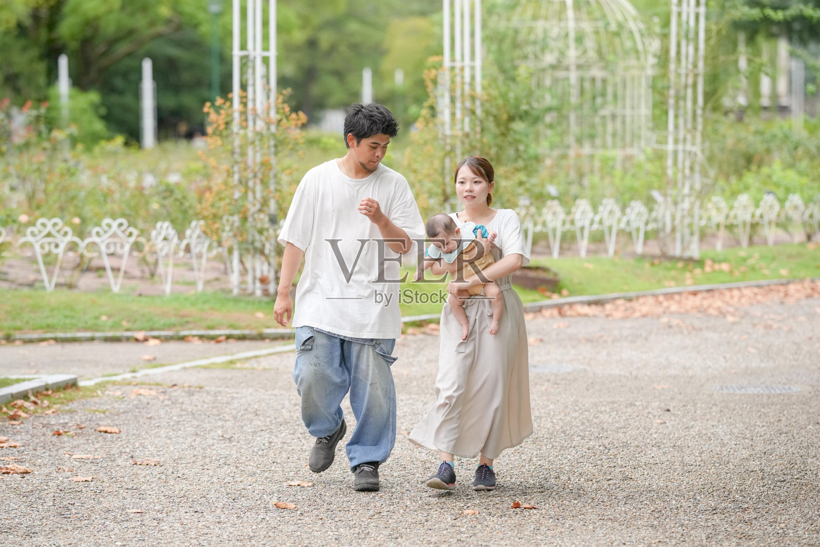 一男一女在公园里带着婴儿散步照片摄影图片