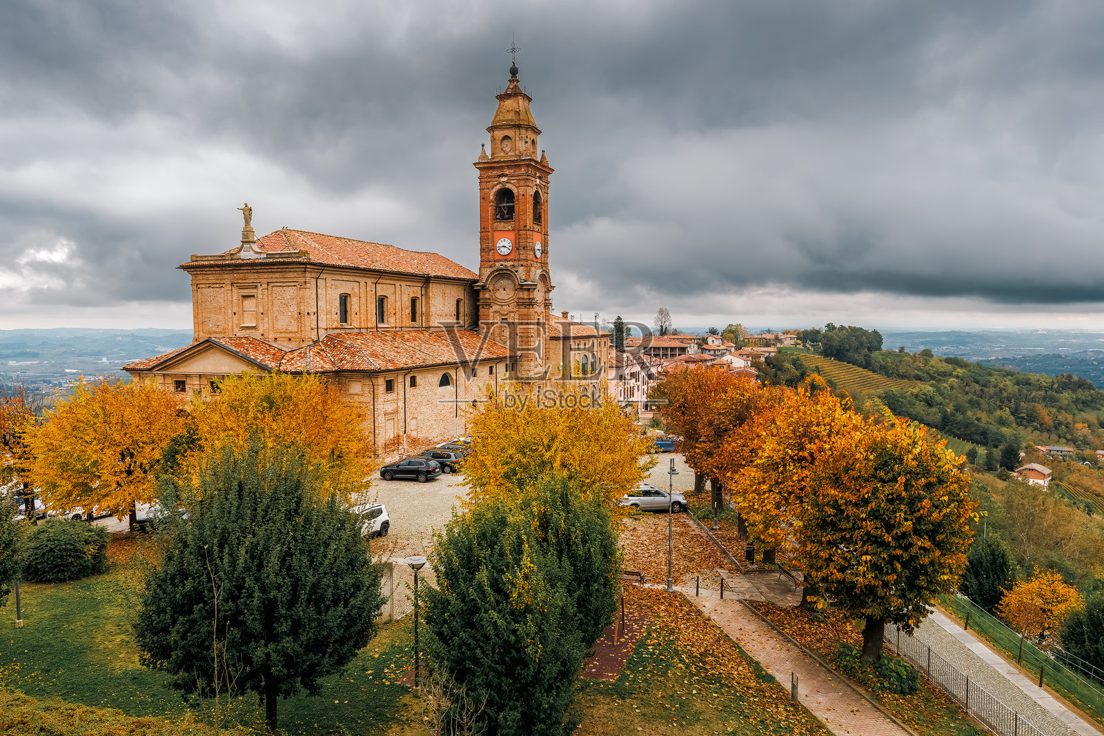 意大利迪亚诺·达尔巴的古老教区教堂矗立在五彩斑斓的秋季树木之间。照片摄影图片