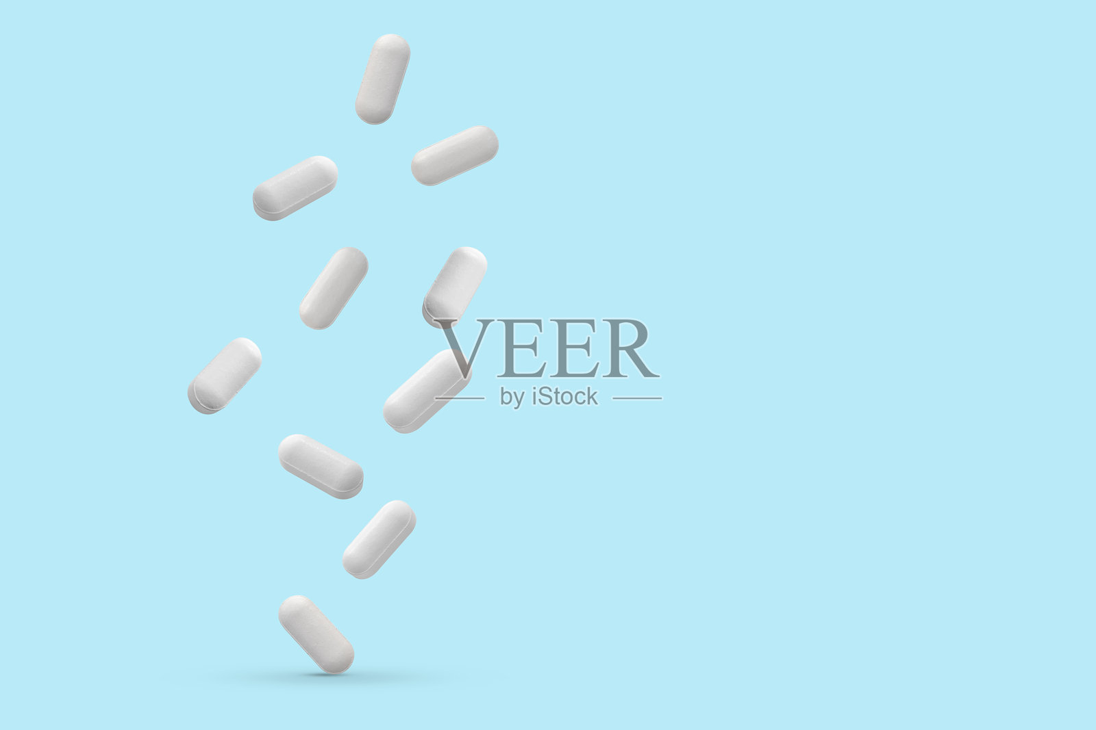 白色药丸在蓝色背景上掉落照片摄影图片