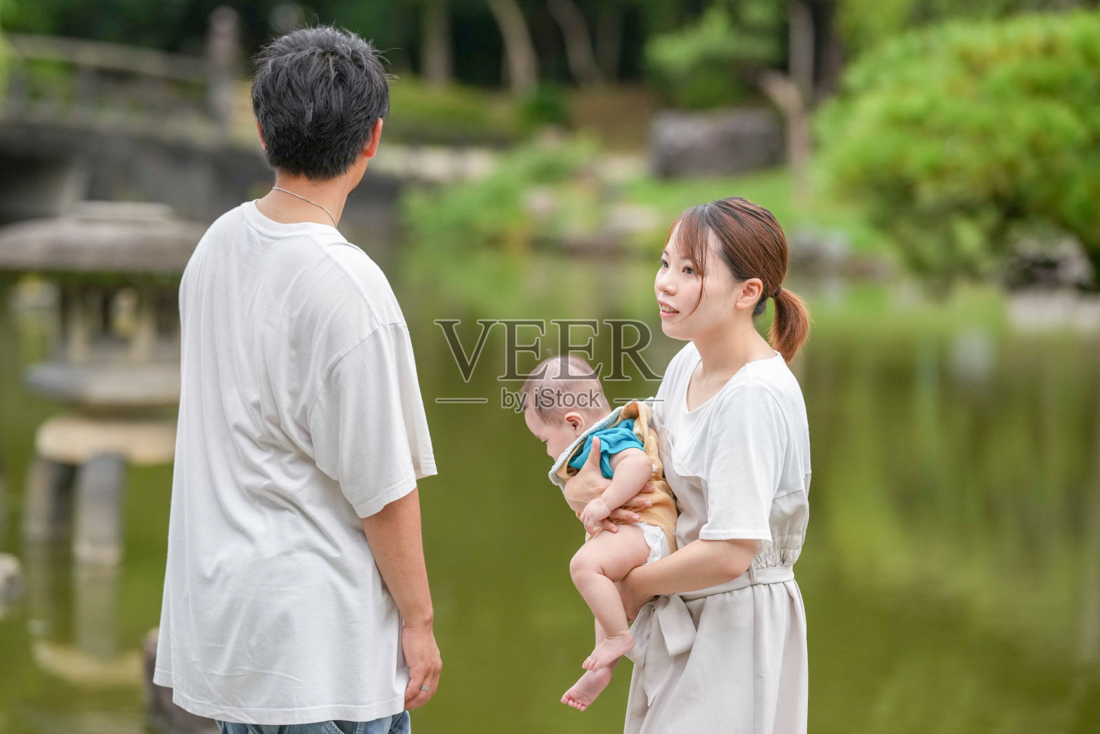 一男一女在公园里抱着一个婴儿照片摄影图片