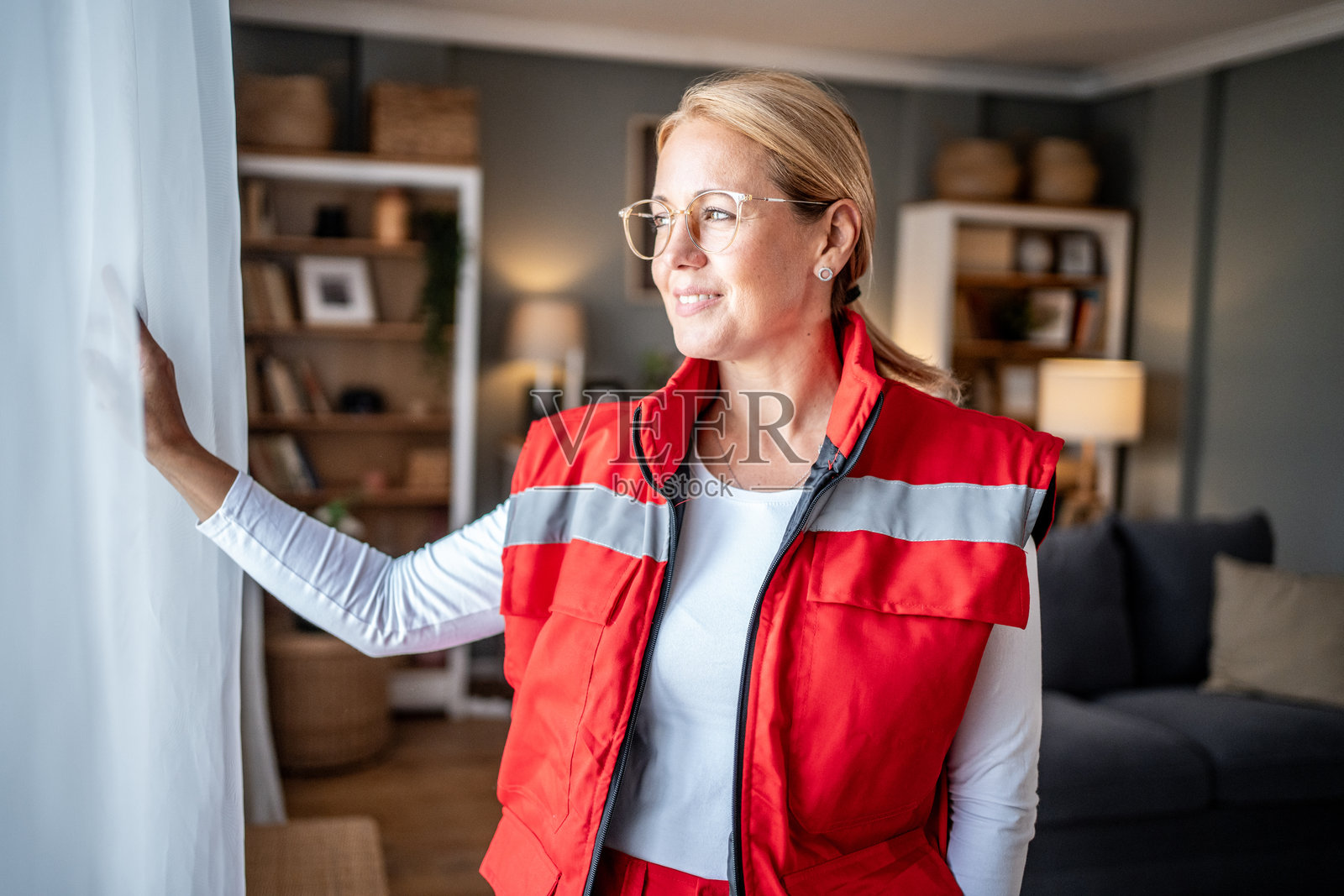 女急救员站在家中望向窗外照片摄影图片