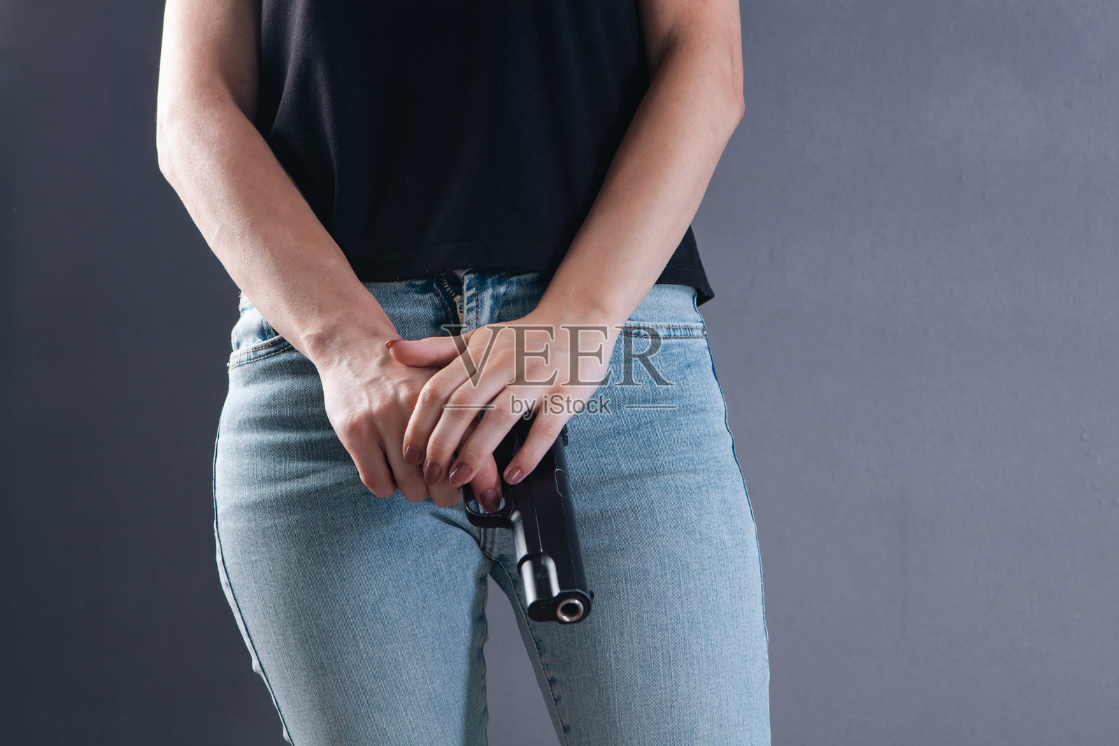 女人手持枪支的特写。背景为灰色。照片摄影图片