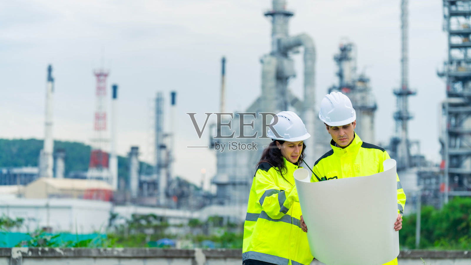 工程师团队在石油炼油厂建设工地上工作。照片摄影图片