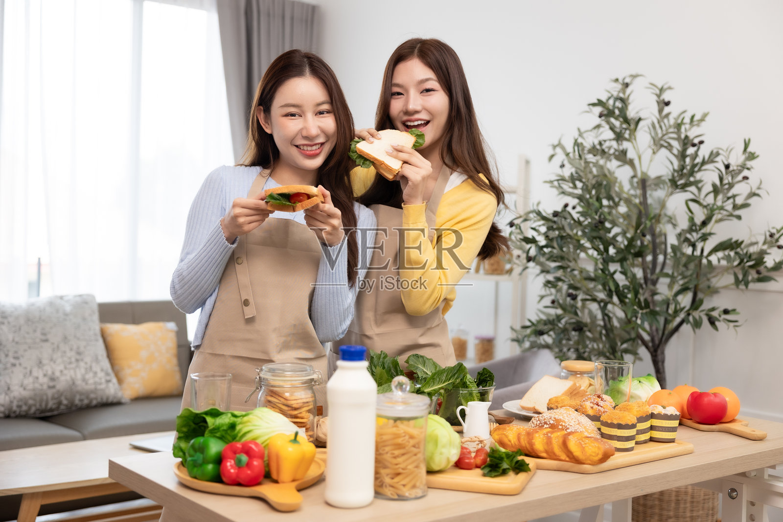 女性在家享用健康早餐。快乐的情侣在厨房准备素食餐。照片摄影图片