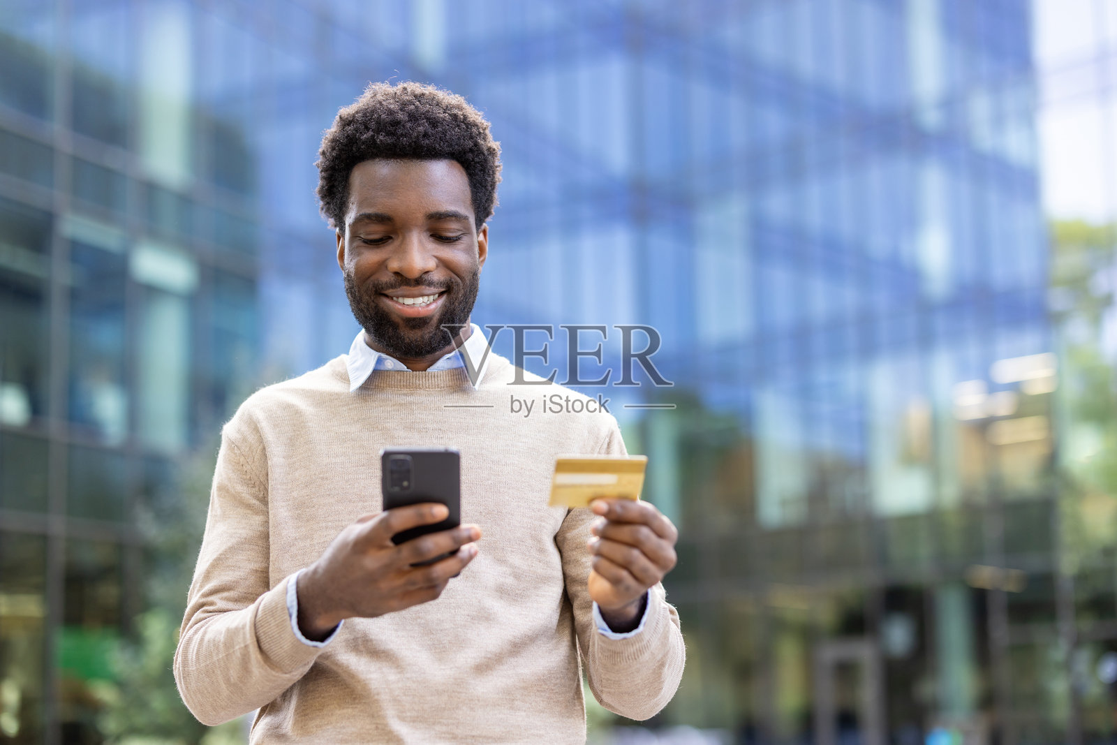 快乐的男人使用信用卡和智能手机进行在线支付。照片摄影图片