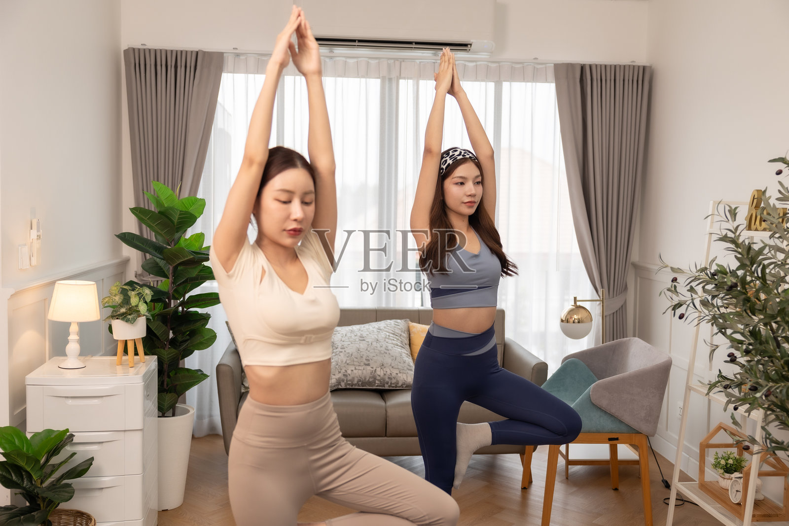 一对情侣，女性在家锻炼。年轻女性在公寓的垫子上做瑜伽，观看笔记本电脑上的教程。在家训练并观看数字平板上的在线课程。照片摄影图片