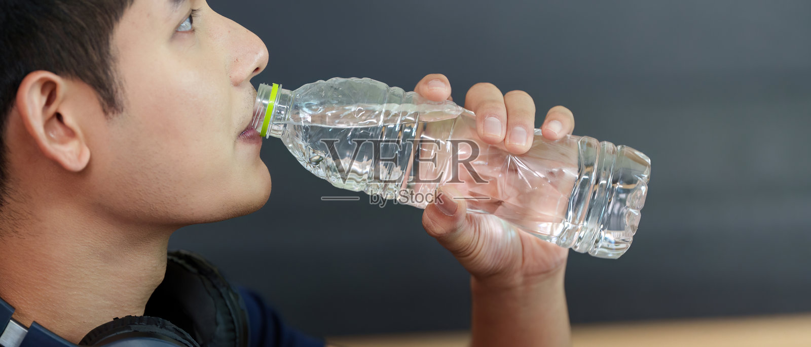 补水。年轻男子从瓶子里喝水，倡导健康与幸福。照片摄影图片