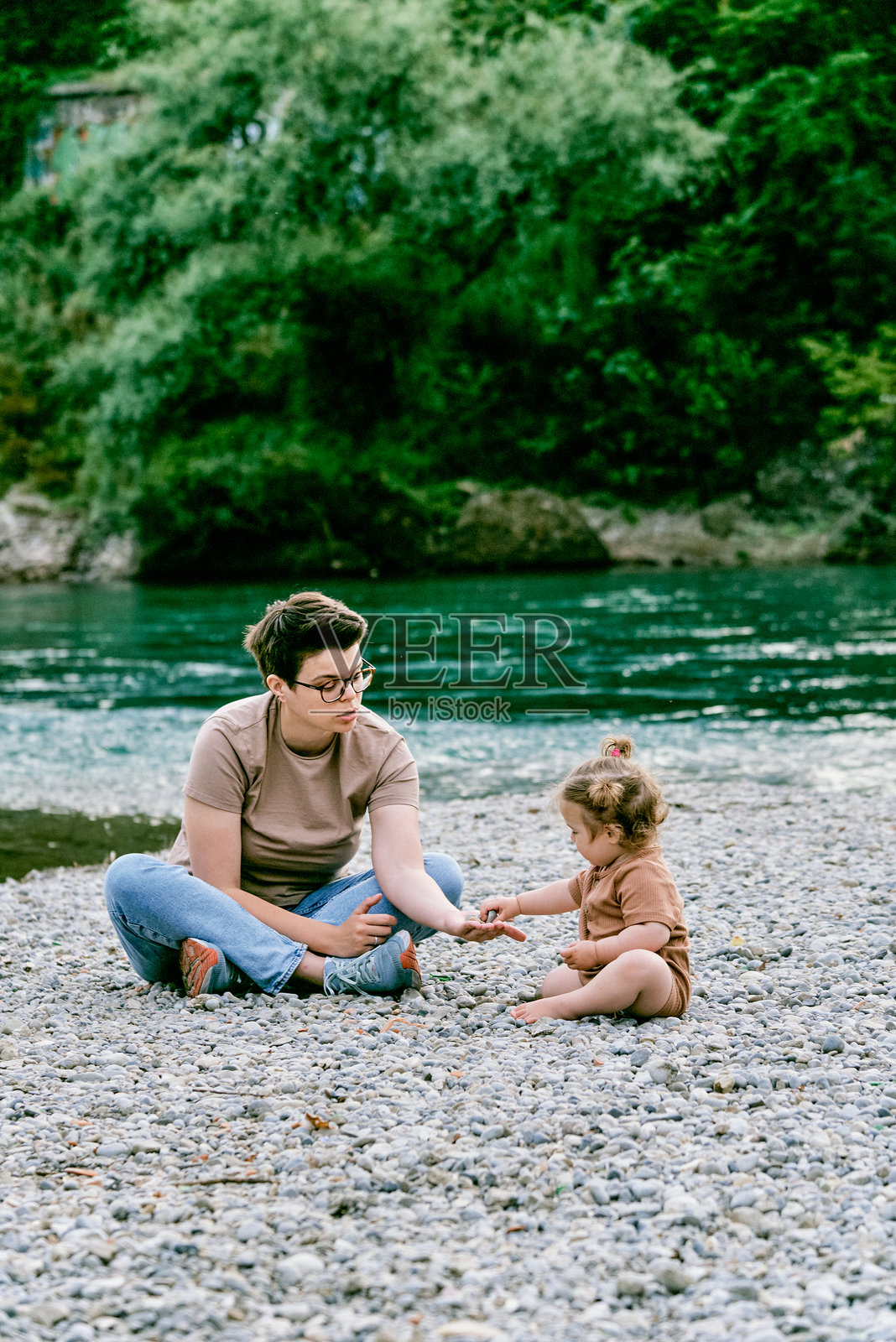 母女在城市河岸的卵石沙滩上玩石头照片摄影图片