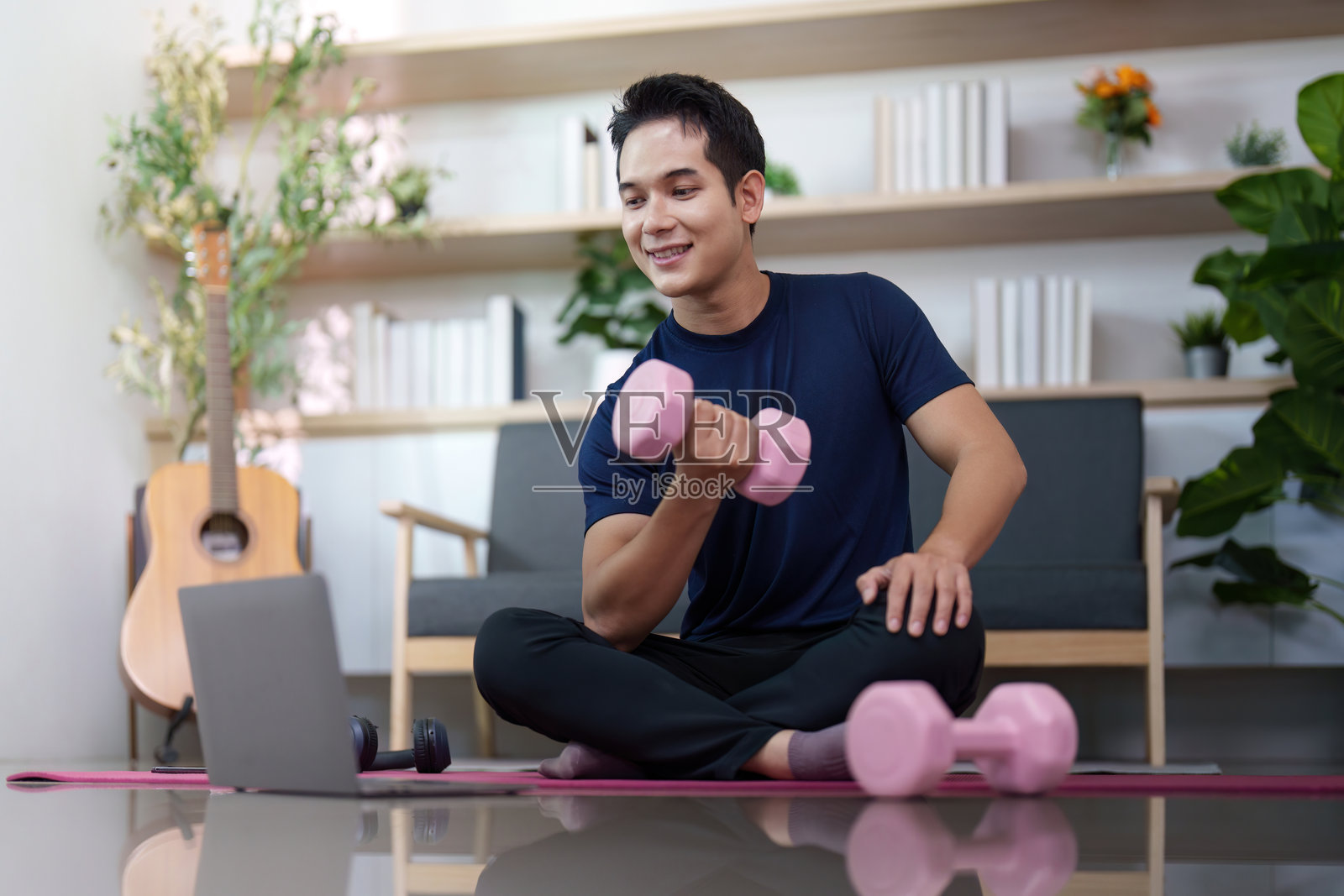 力量训练。个人坐在瑜伽垫上举哑铃。照片摄影图片