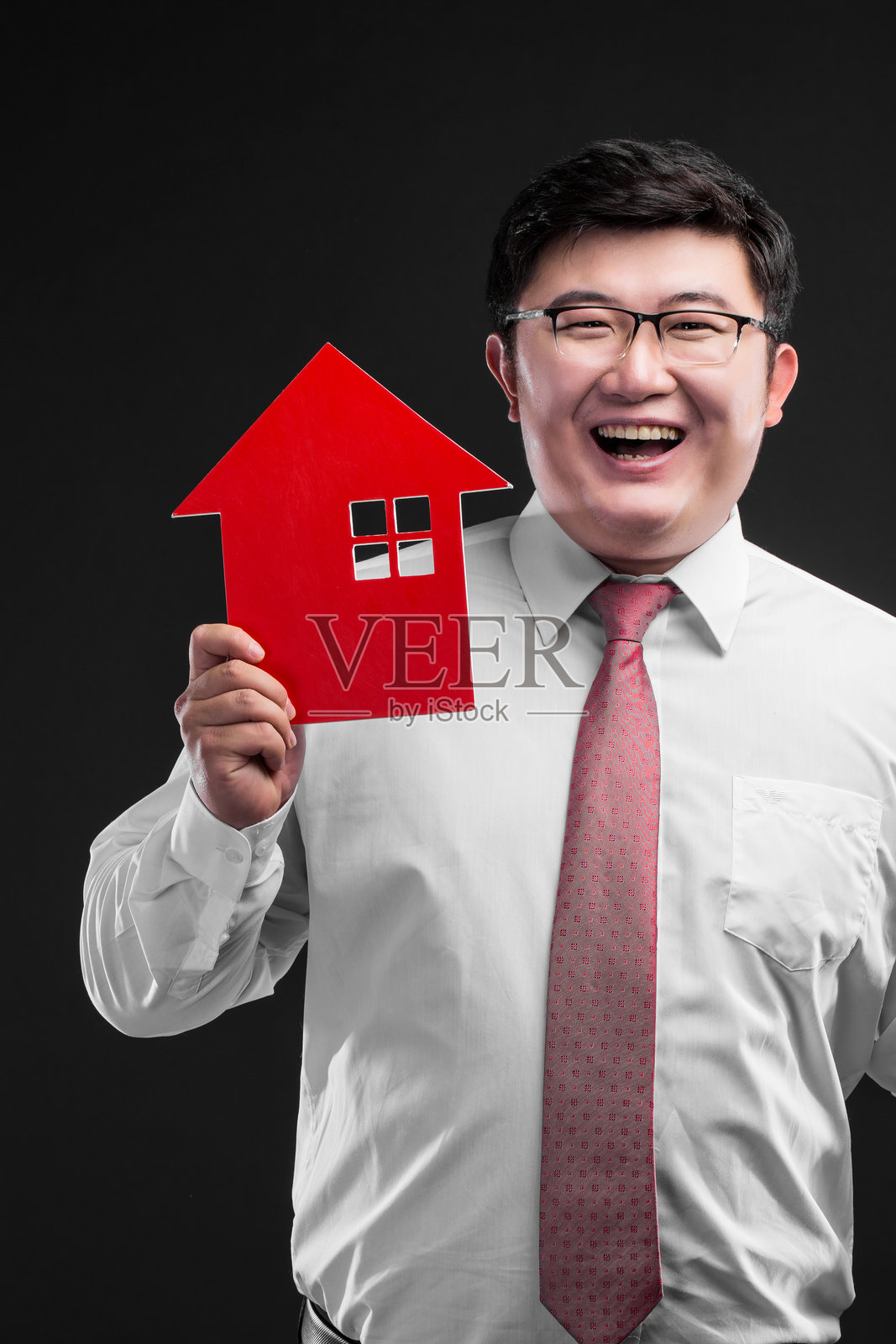 身穿正式服装的男子手持红色房屋模型照片摄影图片