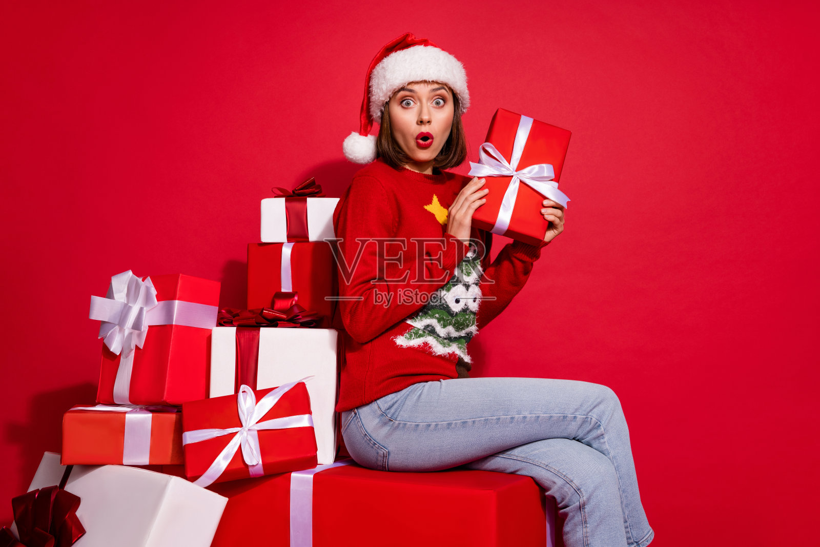 兴奋的年轻女士侧面肖像，快乐地庆祝意外折扣，背景为红色。照片摄影图片