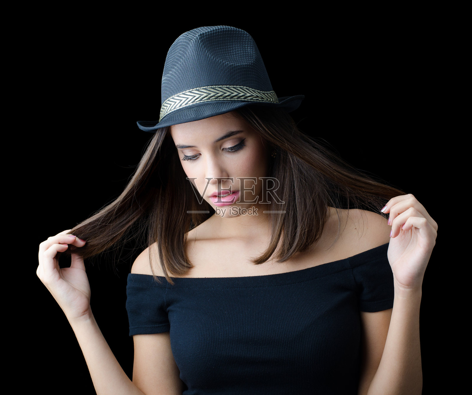 身穿黑色衣服和黑色帽子的美丽女性在摄影棚中摆姿势照片摄影图片