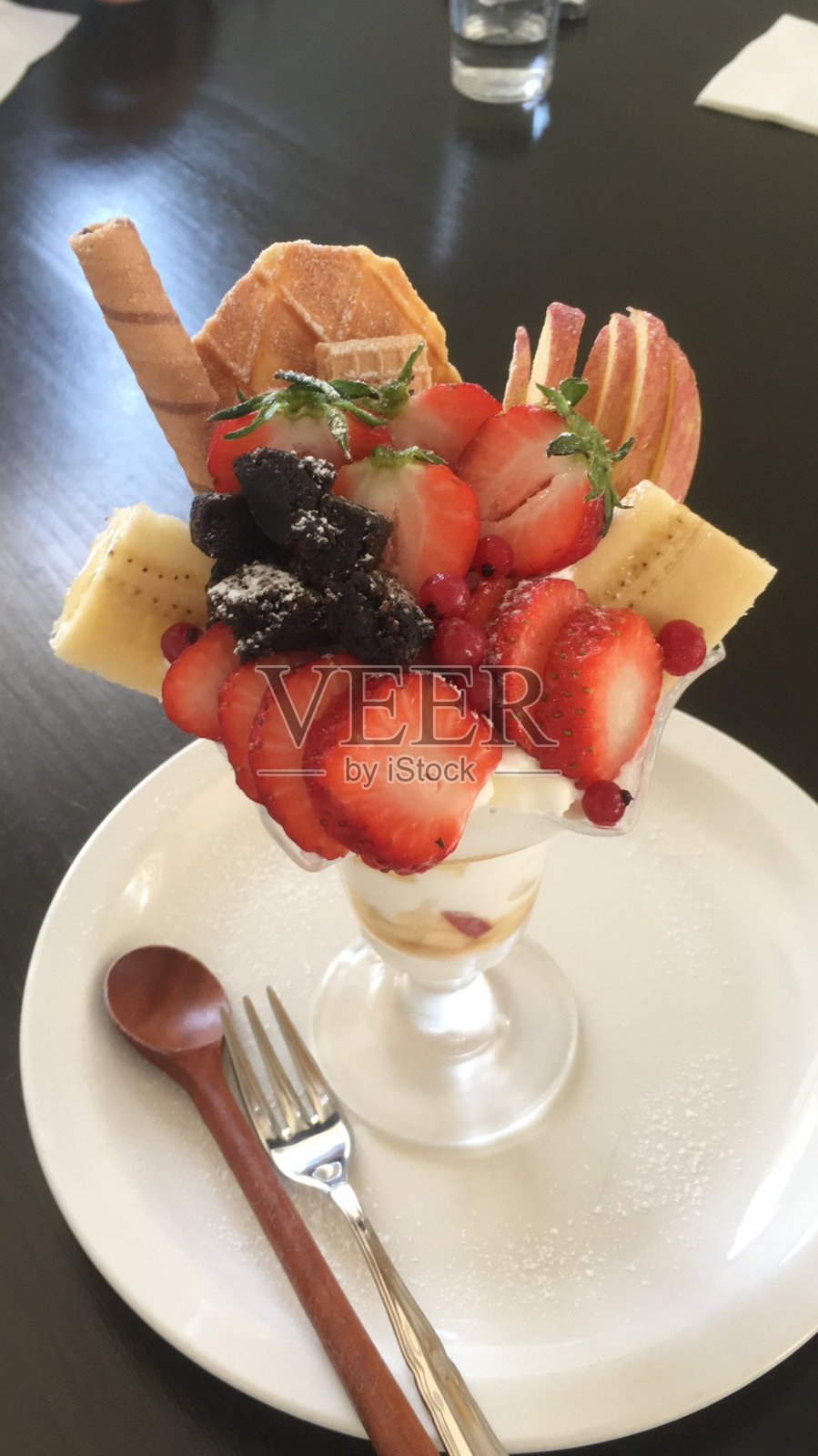 健康的早餐：草莓优格杯，搭配新鲜水果，摆放在乡村风格的白色桌子上。选择性对焦，背景和前景模糊。照片摄影图片